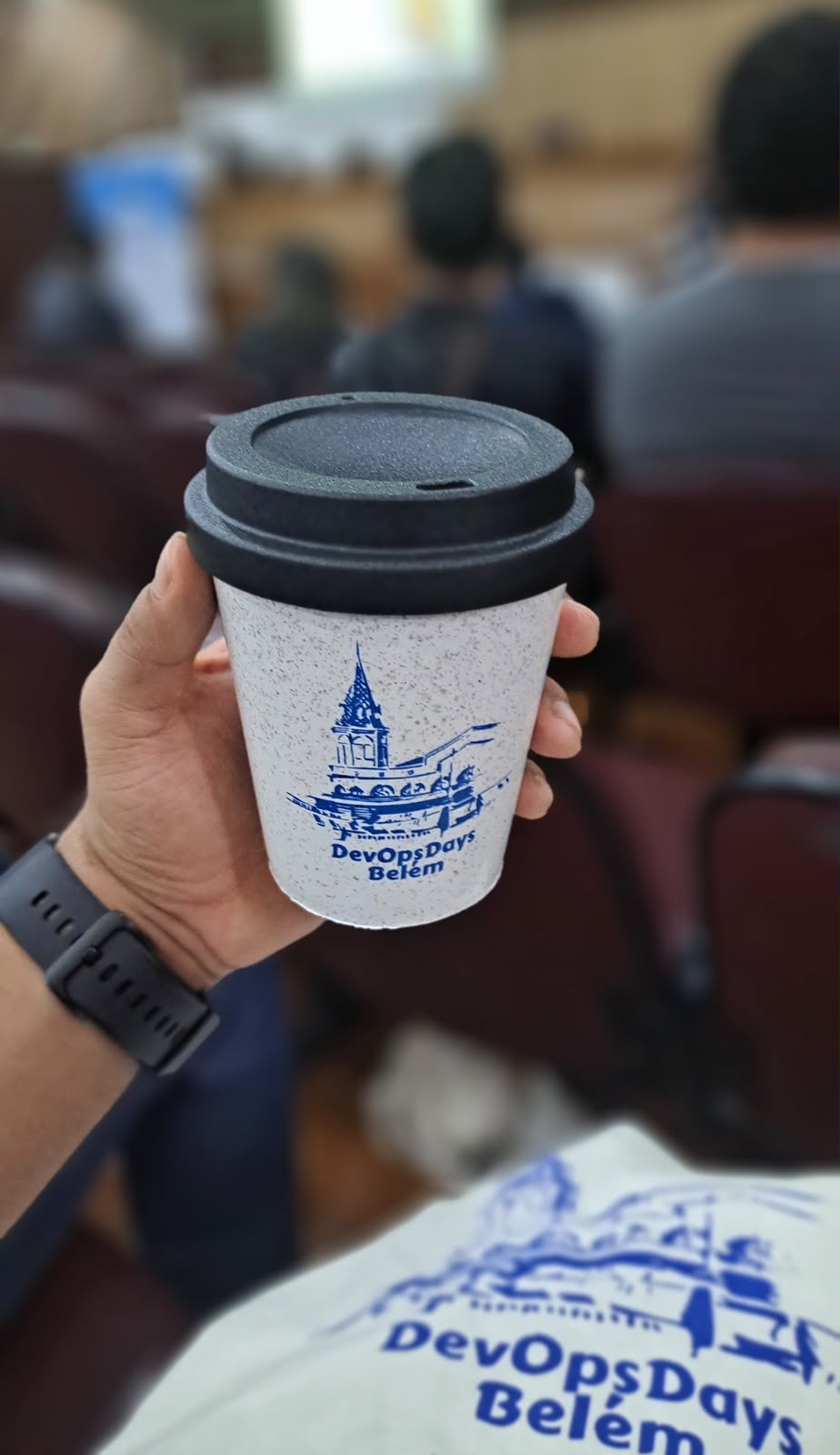 Lucas holding a coffee cup at DevOpsDays Belém